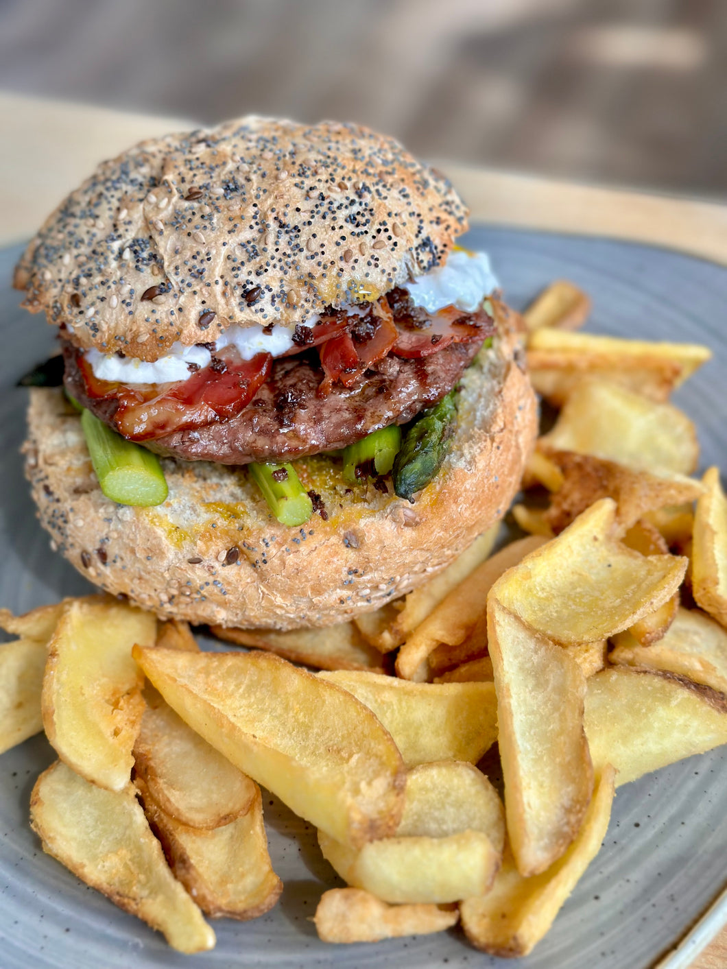 MANZO BURGER. Burger di scottona con asparagi, burrata, pancetta e crumble di olive servito con patate fritte e pane artigianale ai semi
